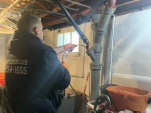 Plumber cleaning a drain pipe in a basement in Old Bridge, NJ